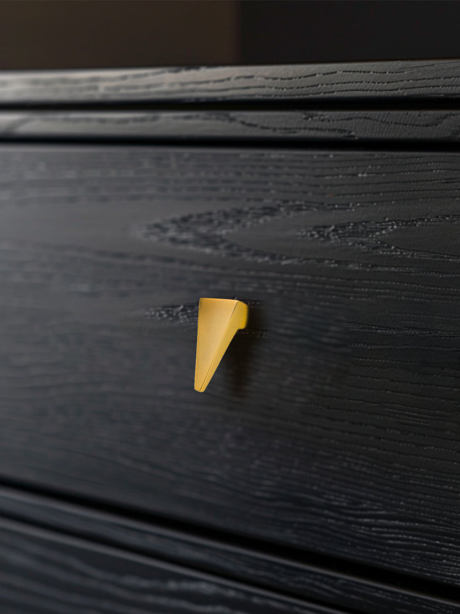 Mockup image of the Trigon knob installed on a black side table drawer, demonstrating its stylish impact in a real-world setting. Keywords: luxury drawer knob, furniture hardware, interior design mockup.