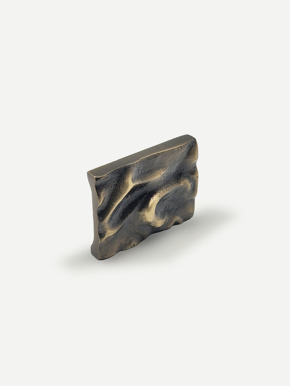 Close-up of the Furl Cabinet Knob in a glossy bronze finish, showcasing its folded brass design that adds a modern, chic touch to any dresser drawer or kitchen cabinet.