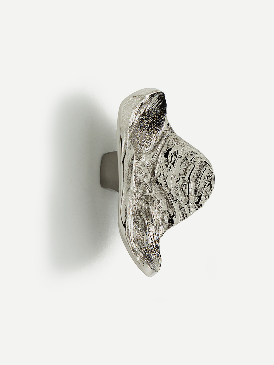 Textured LAVA 2 cabinet and drawer pull in satin nickel, inspired by the organic shapes formed by natural lava flows. Handcrafted with intricate details, this pull adds a sophisticated touch to your cabinets while offering ergonomic functionality.